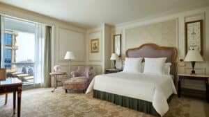Luxurious Four Seasons room with king bed, armchair, and views through large windows.