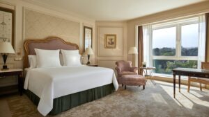 Elegant hotel room at Four Seasons with a large bed, armchair, and scenic window view.