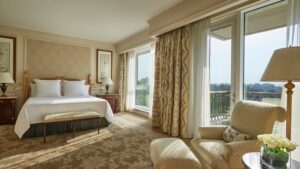 Elegant room at Four Seasons with a bed, armchair, and large windows overlooking a scenic view.