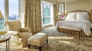 Elegant Four Seasons room with a large bed, armchair, and window view.