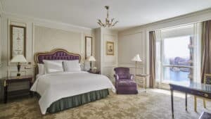 Elegant Four Seasons room with a large bed, armchair, and river view windows.