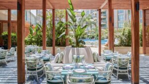 Outdoor patio at Four Seasons Hotel Cairo, with tables, chairs, and lush greenery under a pergola.