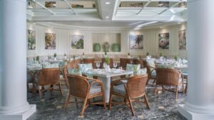 Chic dining at Nile Plaza with wicker chairs, white tables, and art-adorned walls.