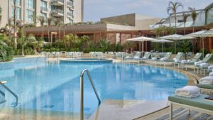 Four Seasons Hotel Cairo at Nile Plaza: pool with lounge chairs, umbrellas, and lush plants.
