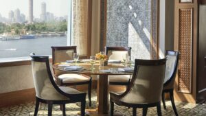Elegant dining table by a window at Four Seasons Hotel Cairo with a cityscape view.