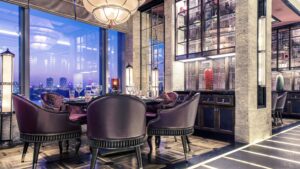 Elegant dining room at Four Seasons Hotel Cairo with plush chairs, glassware, and city views.
