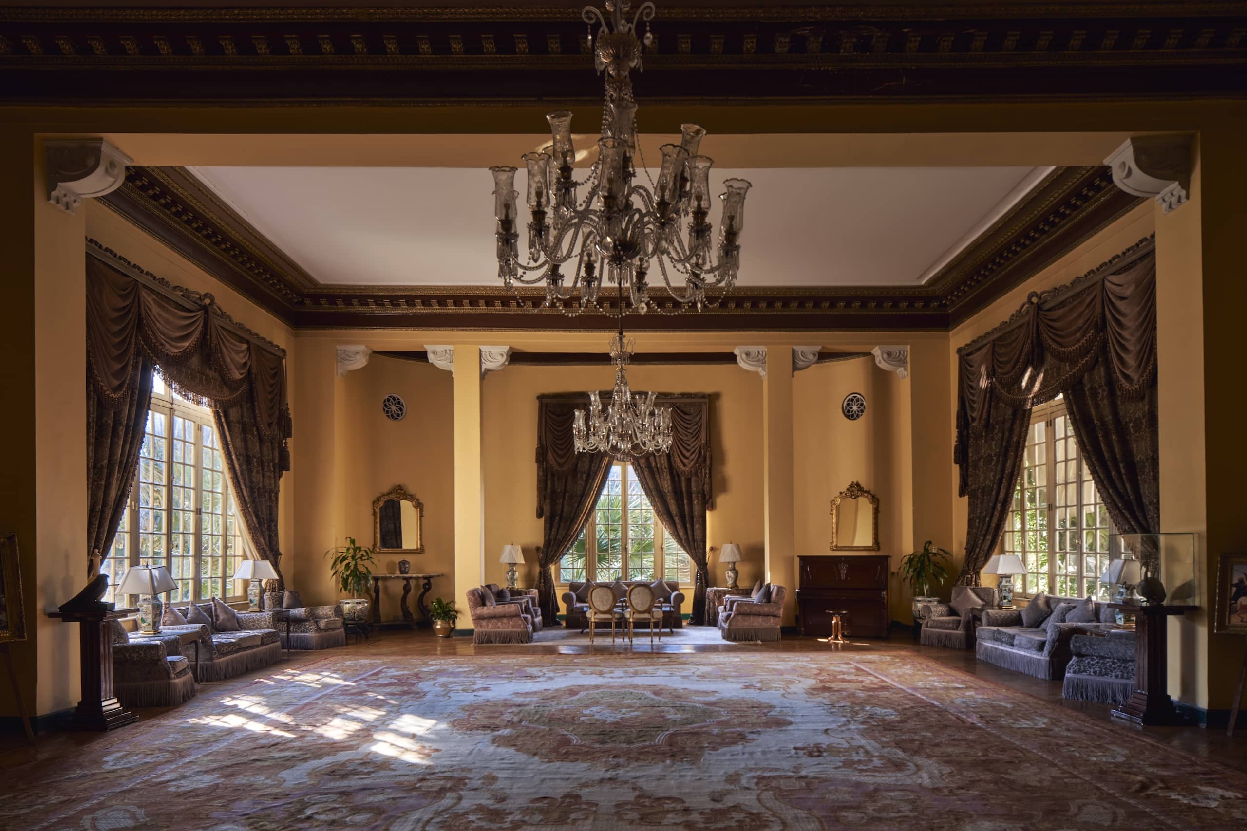 Elegant vintage living room with chandeliers, large Sofitel windows, and ornate drapery.