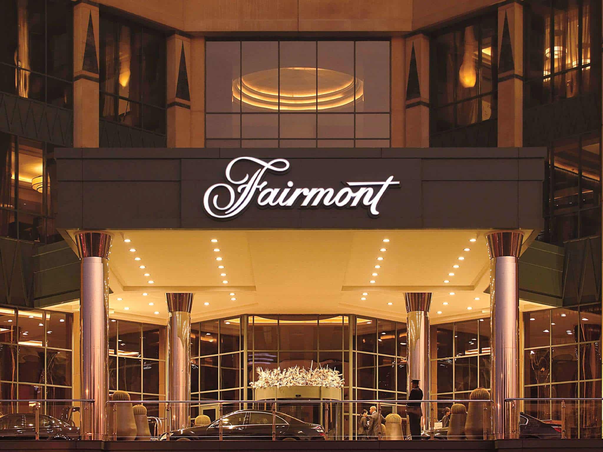 Fairmont Nile City entrance with lit marquee and parked cars at night.