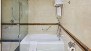 Bathroom at Cairo Marriott with a bathtub, shower, towel rack, and beige tiles.