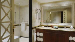 A Cairo Marriott bathroom with a shower, double sink, large mirror, and neatly stacked towels.