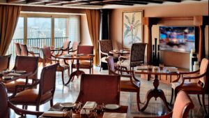 Cairo Marriott Hotel dining area with wooden tables, large windows, and a wall-mounted TV.