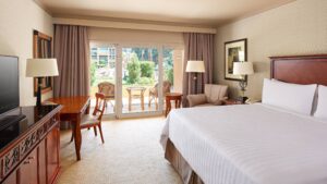 Cairo Marriott room with bed, TV, desk, chairs, and balcony with outdoor seating.