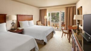 Cairo Marriott Hotel room with two beds, TV, desk, and a stunning balcony view.