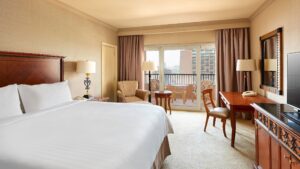 Room at Cairo Marriott Hotel with large bed, desk, chairs, and balcony view.