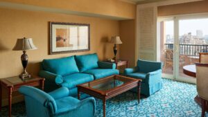 Cairo Marriott room with teal furniture, glass coffee table, and balcony view.