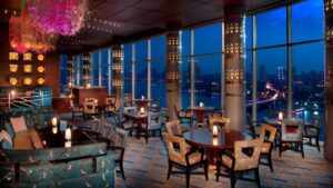 Elegant restaurant at The Nile Ritz-Carlton with large windows overlooking a cityscape at night.