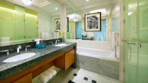 Modern bathroom at The Nile Ritz-Carlton: double sinks, large mirror, bathtub, framed artwork.