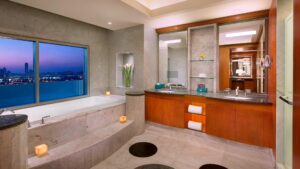 Modern bathroom at The Nile Ritz-Carlton with tub, city views, and wood-accented vanity.