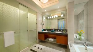 Modern bathroom at The Nile Ritz-Carlton with glass shower, large mirror, and twin sinks.