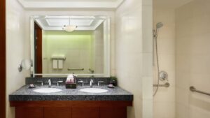 Modern bathroom at The Nile Ritz-Carlton with double sinks, large mirror, and wall showerhead.