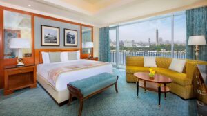 The Nile Ritz-Carlton room with bed, seating area, city view, and expansive windows.