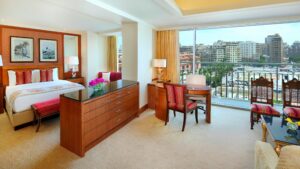 Hotel room at The Nile Ritz-Carlton with king bed, desk, and large window city view.