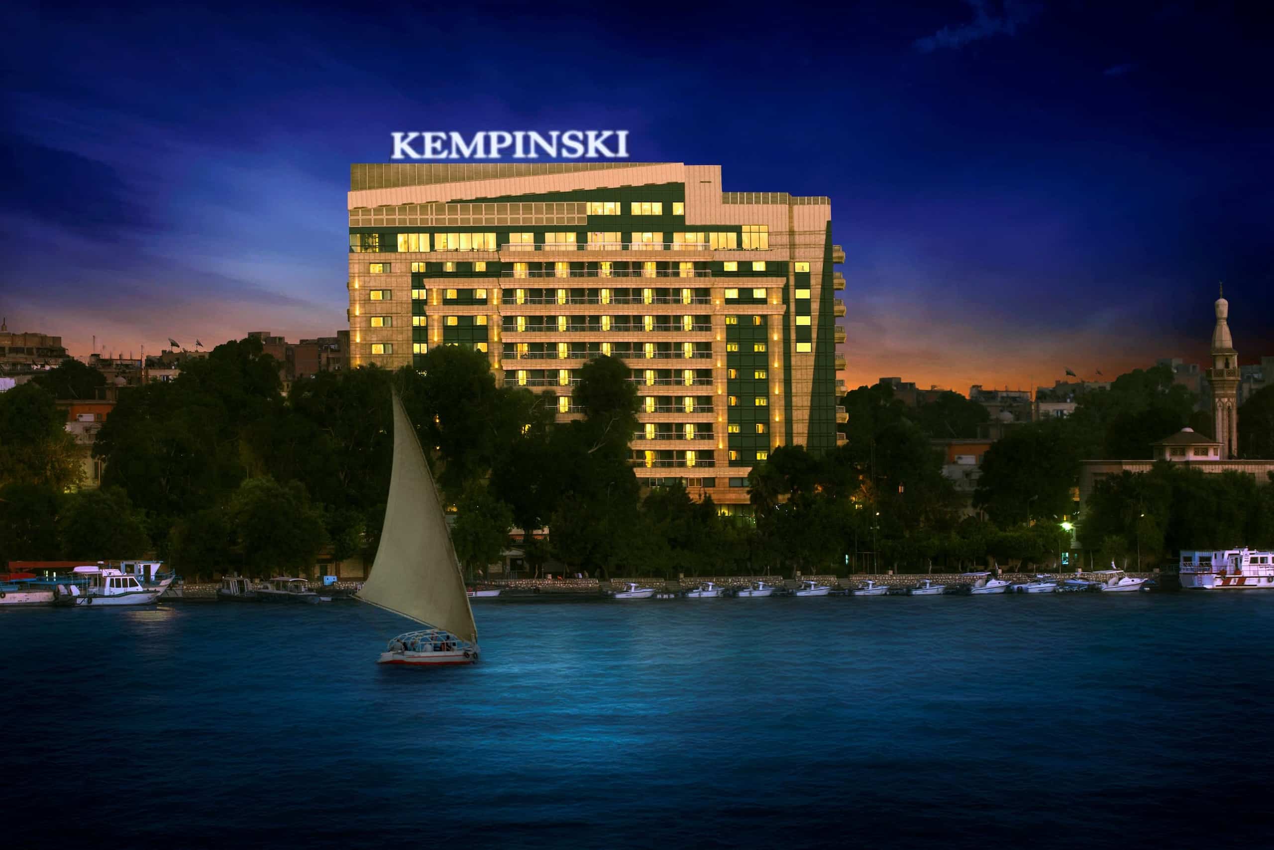 Sailboat on river with Kempinski Nile Hotel glowing in the background at dusk.