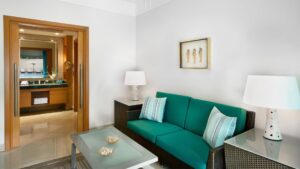 Modern lounge at The Nile Ritz-Carlton with green sofa, striped pillows, glass tables by the bathroom.