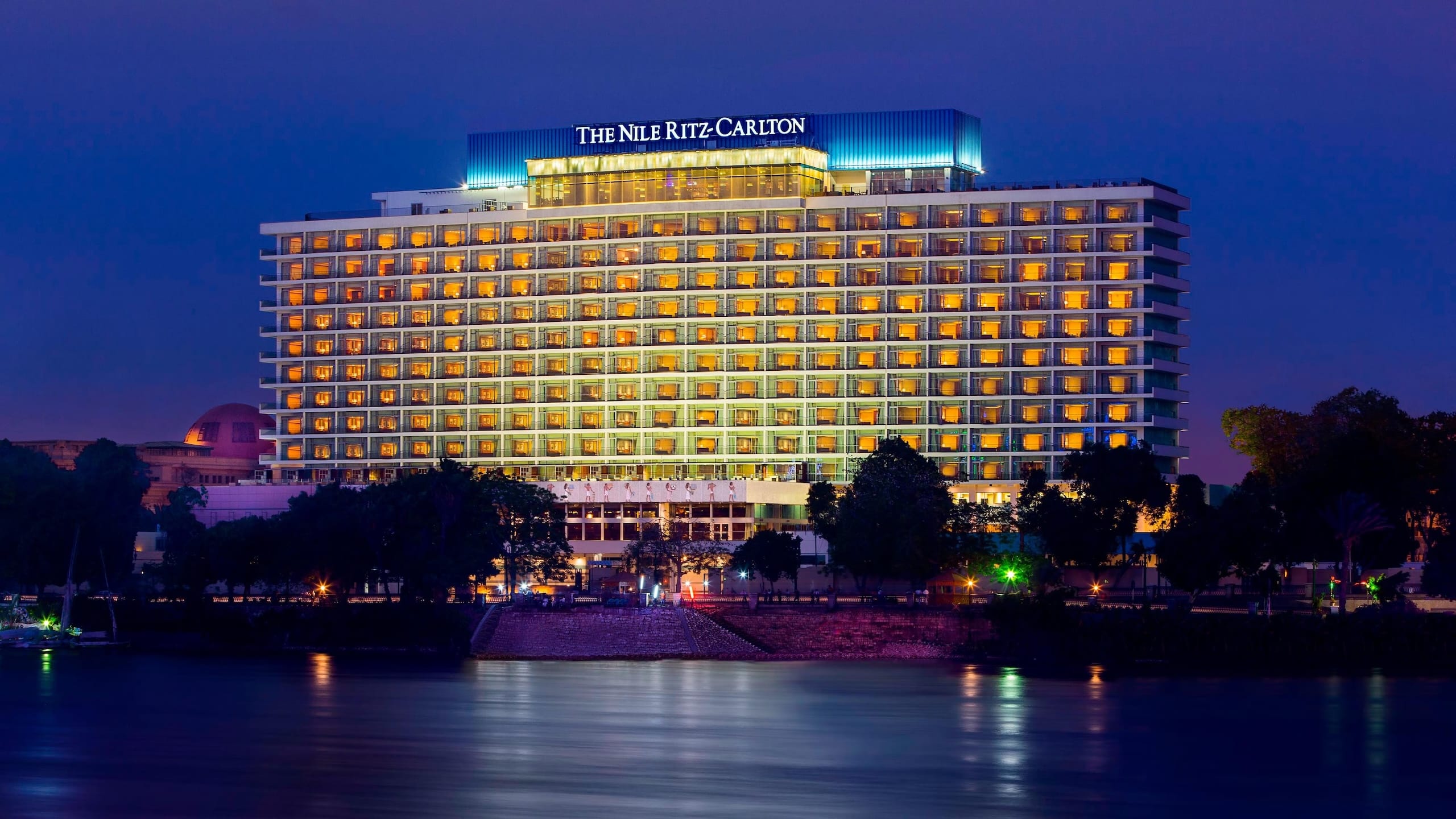 The Nile Ritz-Carlton shines by the waterfront at dusk.