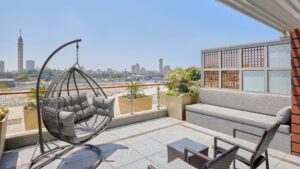 Rooftop patio at The Nile Ritz-Carlton with hammock chair, skyline view, and potted plants.