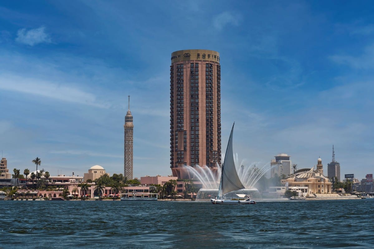 Sailboat on the river with Sofitel Cairo and cityscape in the background.
