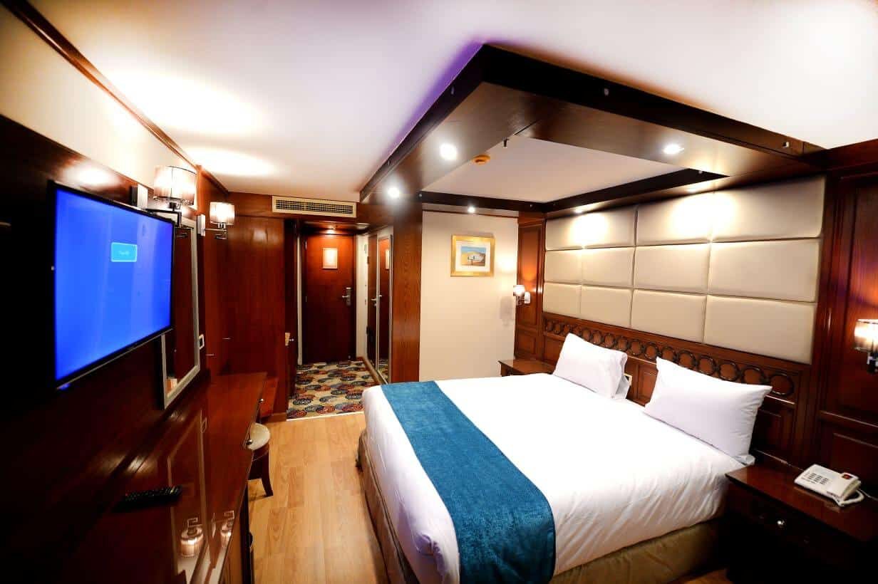 Modern 5* hotel room with a large bed, TV, and MS Classic Blue Shadow II lighting.