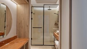 Modern bathroom at Hyatt Centric Cairo West with glass shower, round mirror, and wooden vanity.