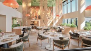 Modern, sunlit restaurant at Hyatt Centric Cairo West with wicker chairs and a striking mural.