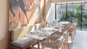 Modern restaurant at Hyatt Centric Cairo West with wicker chairs, mural, and lush garden view.