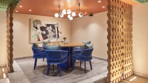 Round table with blue chairs at Hyatt Centric Cairo West, framed by art and wooden partitions.