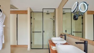Modern bathroom at Hyatt Centric Cairo West with glass shower, double sinks, and lit mirror.