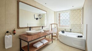 Modern Hyatt Centric Cairo West bathroom with double sinks, large mirror, and beige tile walls.