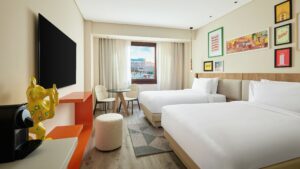 Modern Hyatt Centric Cairo West room with two beds, wall art, TV, and city view window.