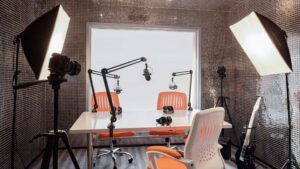A podcast studio setup at Hyatt Centric Cairo West with mics, headphones, lights, and orange chairs.