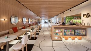 Modern café at Hyatt Centric Cairo West with round tables, wall mirrors, and a snack counter.