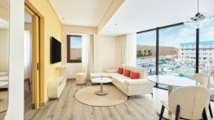 Modern Hyatt Centric Cairo West suite with a sofa, table, TV, and pool-view window.