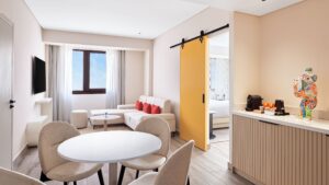 Modern Hyatt Centric Cairo West suite with sitting area, dining table, and yellow sliding door.